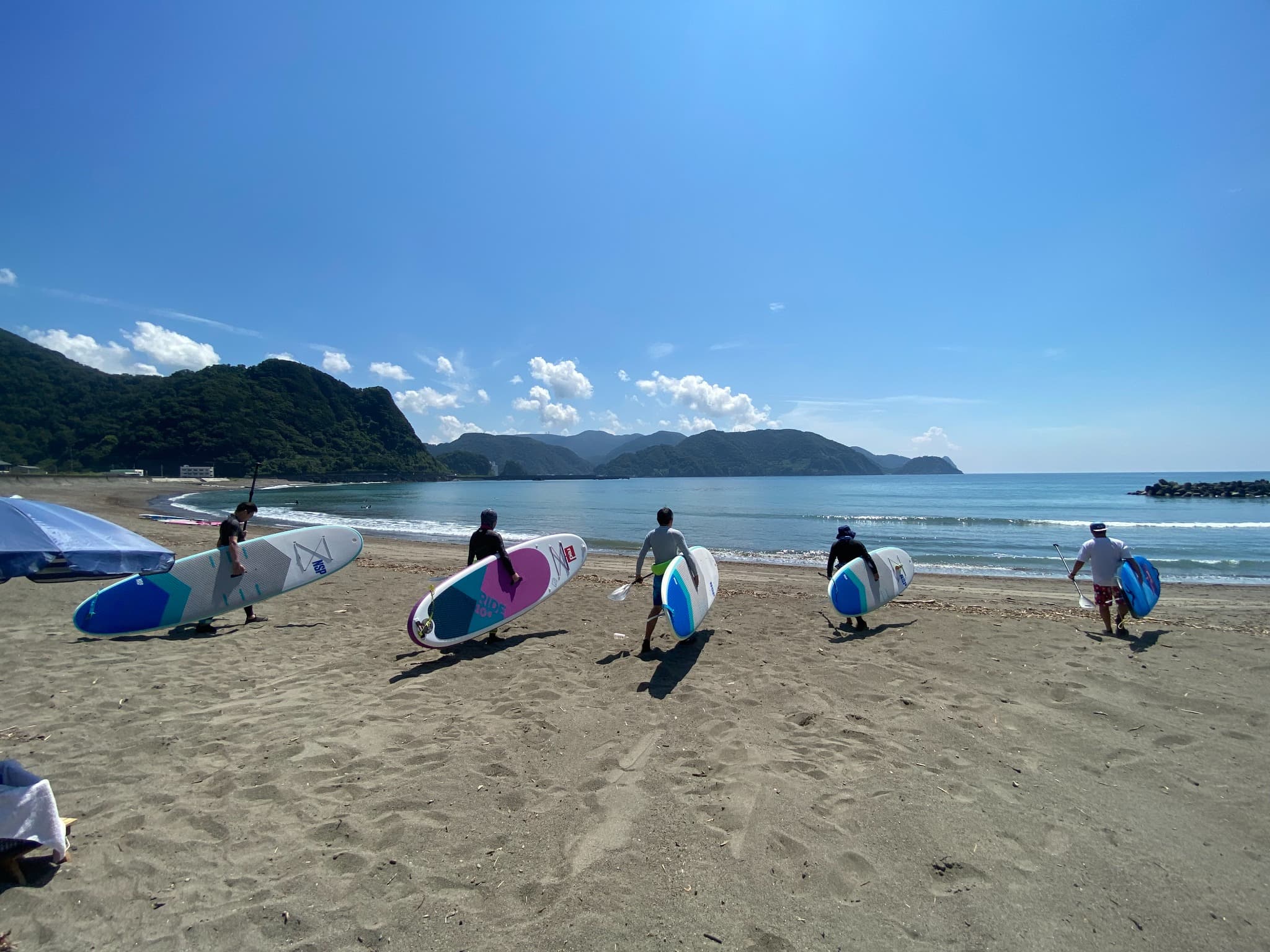 SUP tour group walking from the beach toward the sea in Nishi-Izu